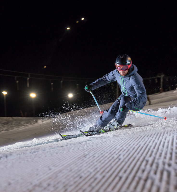 Ein Skifahrer fährt Nachts die Strecke hinunter.