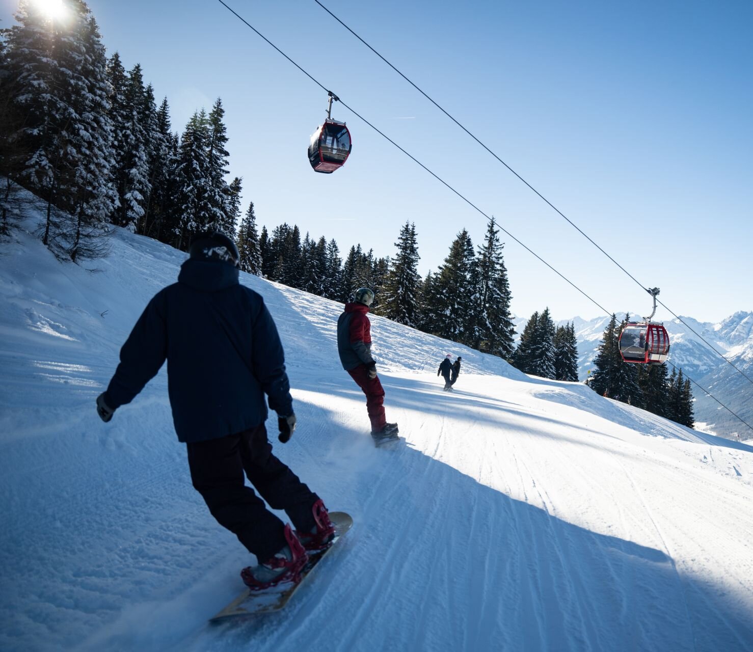 Snowboarder und Skifahrer fahren eine Piste hinunter.