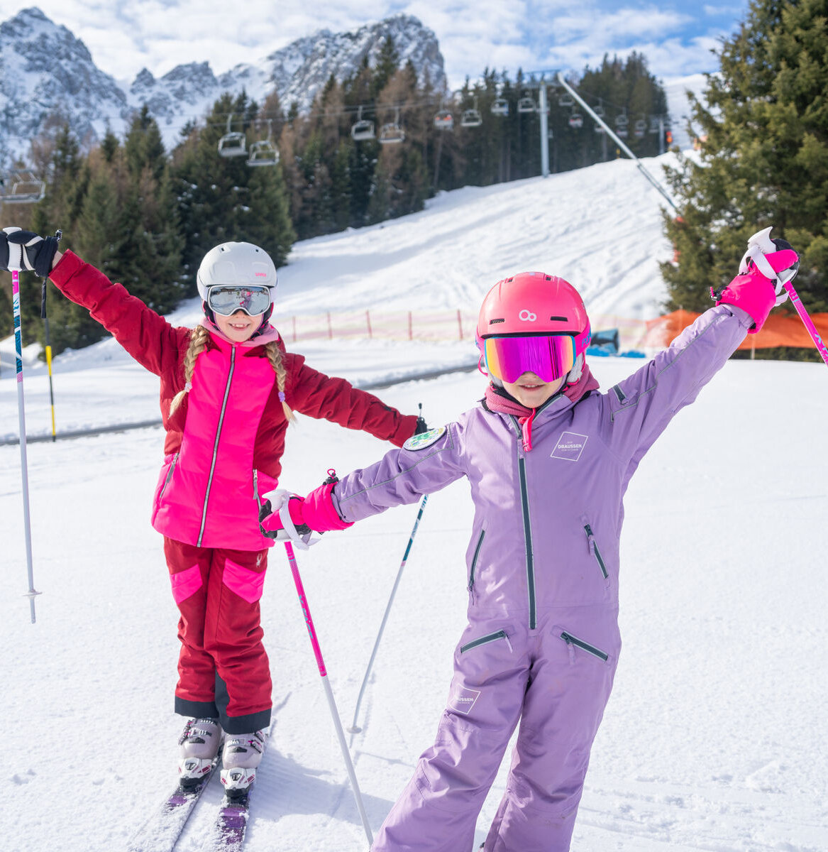 Zwei Mädchen in pinker Skikleidung.