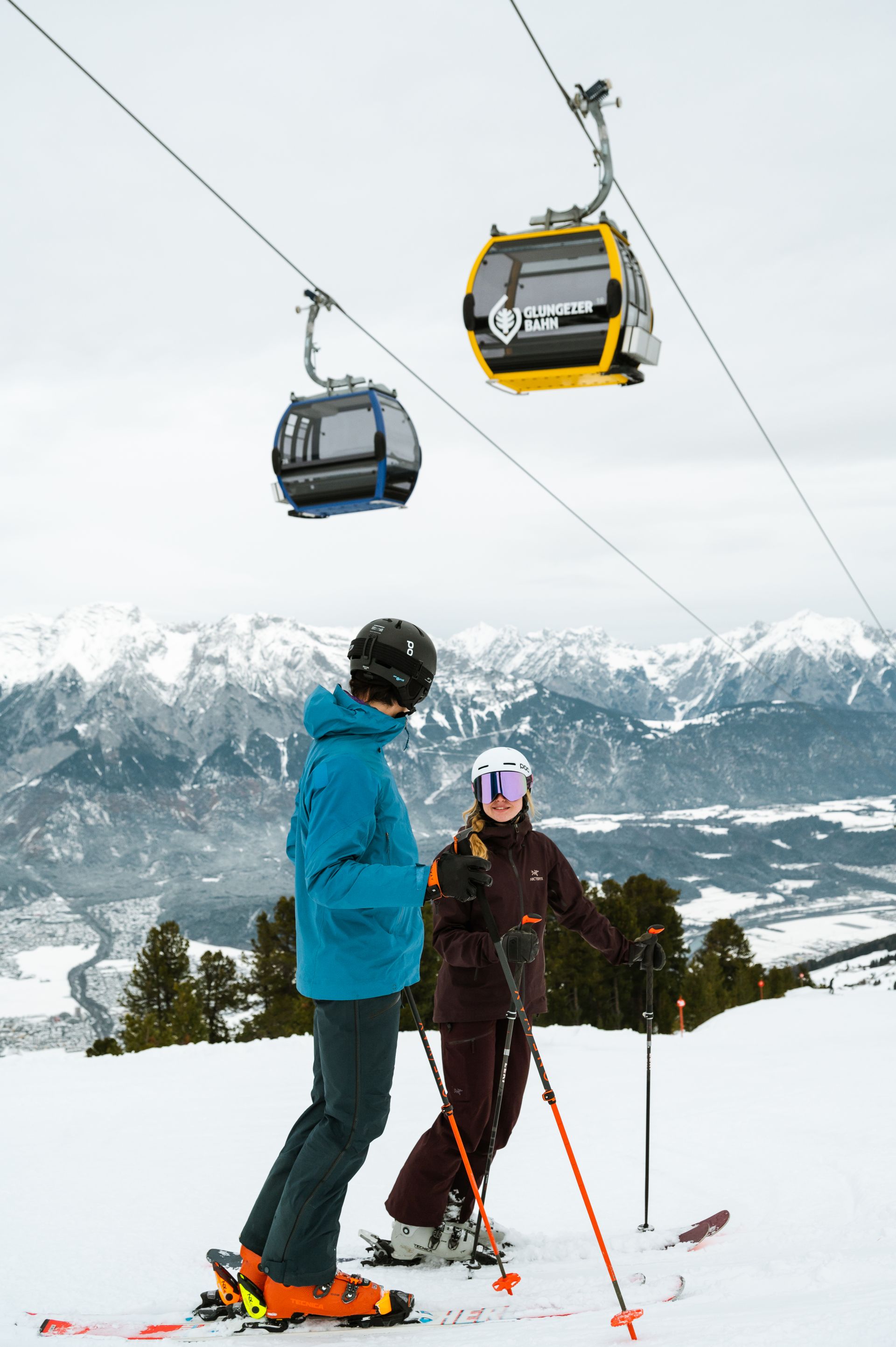 Zwei Skifahrer stehen unter einer Gondelbahn.