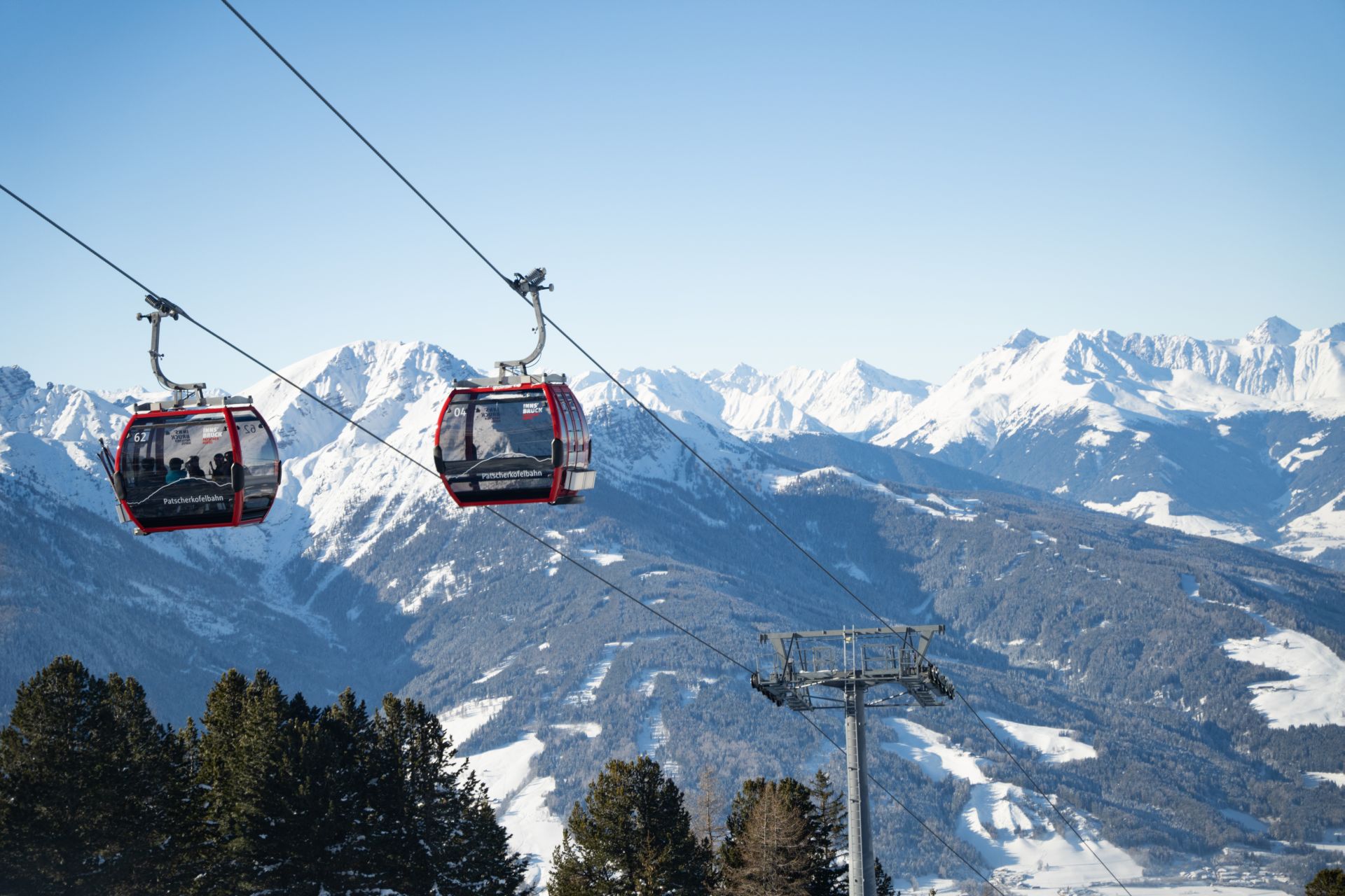 Gondelbahnen umgeben von einem Bergpanorama.